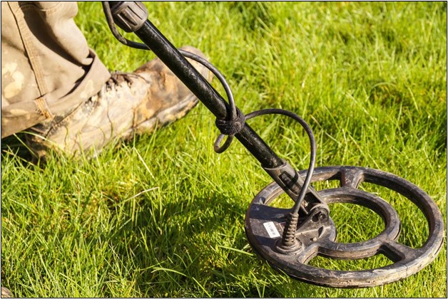 Image showing a man using a metal detector on grass.