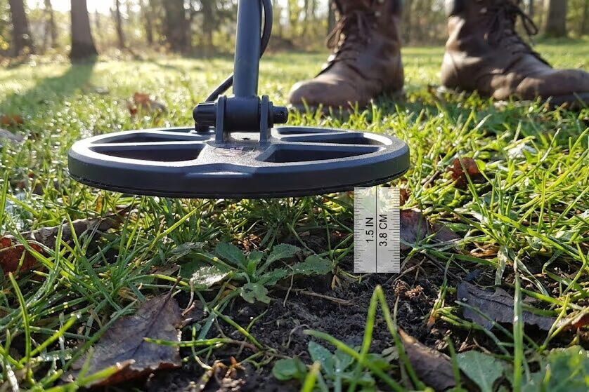 Metal detector coil positioned 1-2 inches above ground surface demonstrating optimal height
